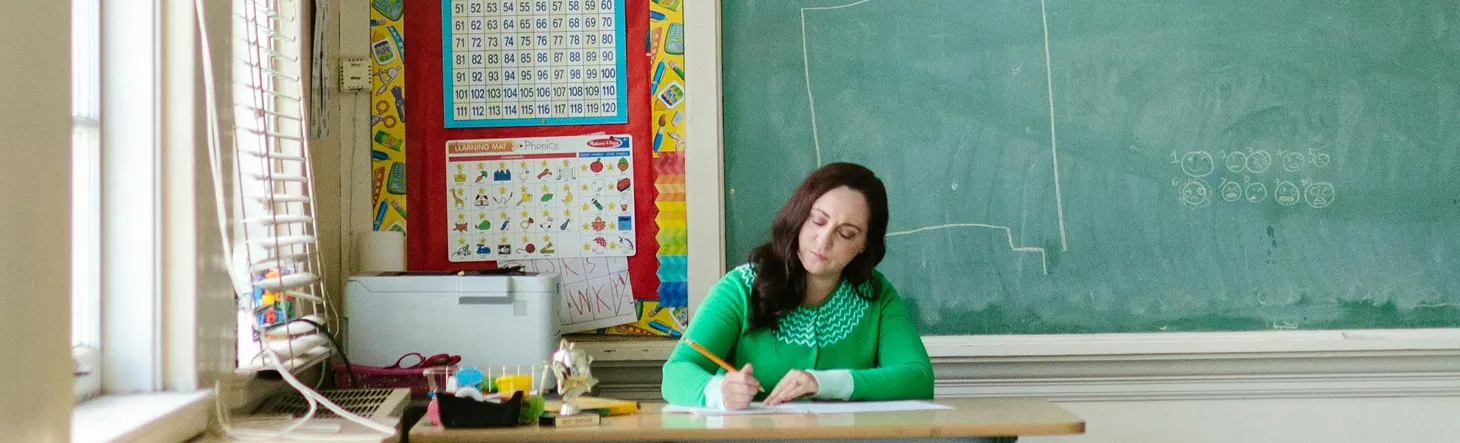A teacher working at her desk in a classroom
