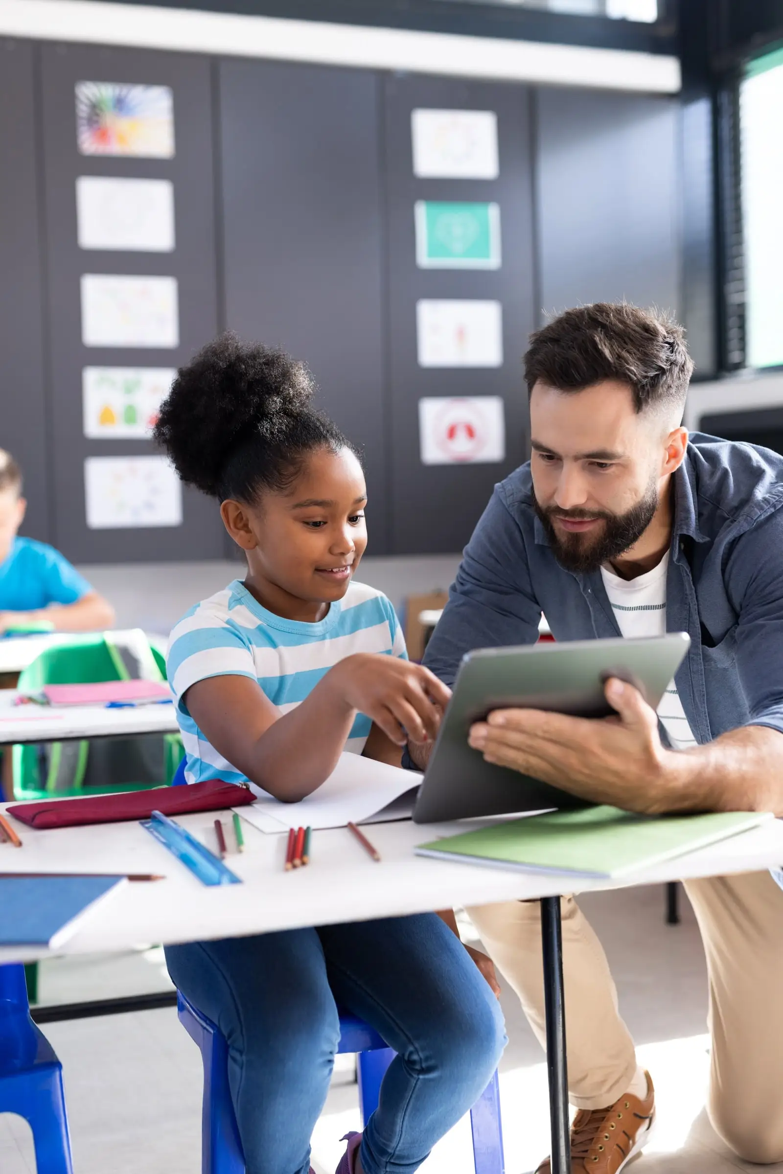 A teacher and student reviewing work on a tablet
